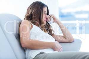 Sad pregnant woman sitting on sofa