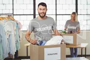 Portrait of smiling volunteer separating clothes from donation b