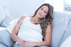 Sad pregnant woman leaning on sofa