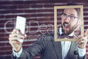 Excited man taking selfie while holding frame