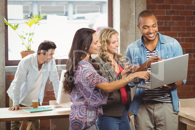 Smiling business people pointing towards laptop