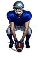 American football player with ball crouching