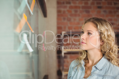 Businesswoman looking at glass board in creative office