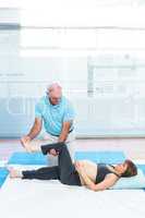 Cheerful therapist kneading to pregnant woman lying on mattress