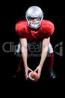 American football player bending while holding ball