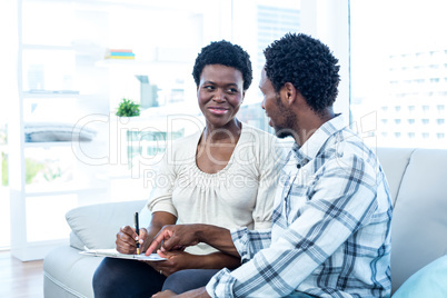 Man talking with pregnant wife while pointing on paper