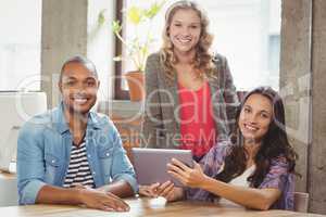 Portrait of smiling business people discussing over tablet