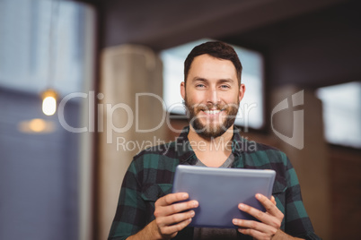 Portrait of cheerful businessman holding digital tablet