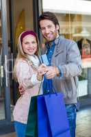 Smiling couple showing credit card and shopping bags