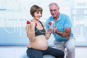 Male instructor teaching pregnant woman to exercise