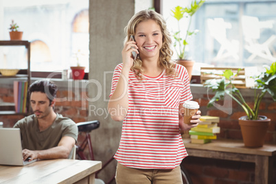 Portrait of businesswoman talking over phone in office