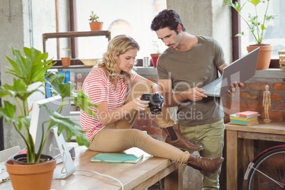 Businesswoman showing digital camera to colleague