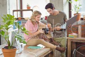 Businesswoman showing digital camera to colleague