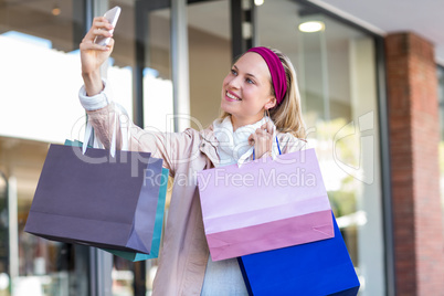 Smiling woman with shopping bags taking selfies