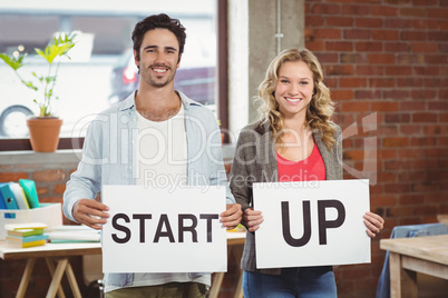 Portrait of smiling business people showing card with start up t
