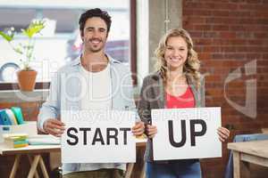 Portrait of smiling business people showing card with start up t