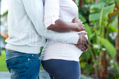 Husband embracing while wife touching her belly