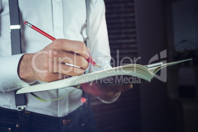 Midsection of businessman writing in his notepad