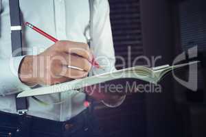 Midsection of businessman writing in his notepad