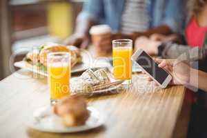 Cropped image of woman using phone while having breakfast in off