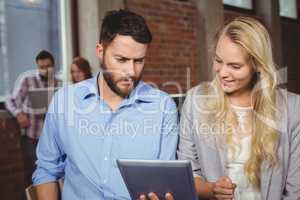 Man and woman looking towards digital tablet