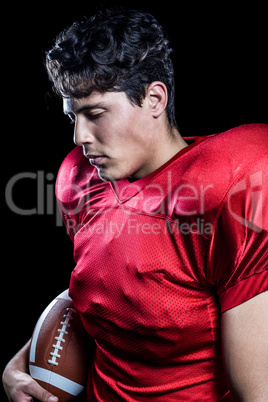 American football player holding ball while eyes closed