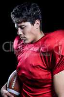 American football player holding ball while eyes closed