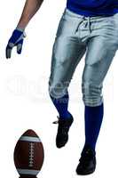 Low section of American football player kicking ball