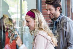 Smiling couple going window shopping and pointing at clothes