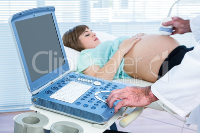 Pregnant woman lying while doctor performing ultrasound test