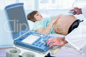 Pregnant woman lying while doctor performing ultrasound test
