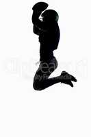 Silhouette American football player jumping while holding ball