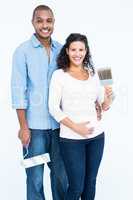 Portrait of happy couple with roller and paintbrush