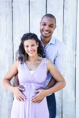 Portrait of smiling pregnant with husband touching belly