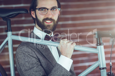 Portrait of smart smiling hipster carrying bicycle