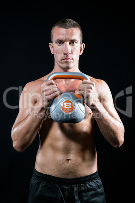 Confident shirtless athlete working out with kettlebell