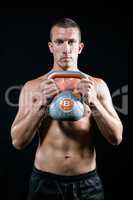 Confident shirtless athlete working out with kettlebell