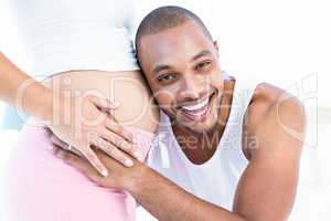Happy man listening to belly of pregnant wife