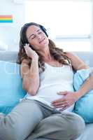 Pregnant woman enjoying music at home