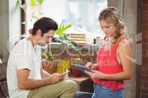 Woman with digital tablet while man using smartphone in office