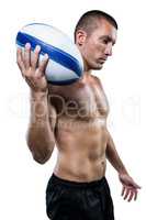 Confident shirtless rugby player holding ball
