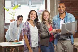 Portrait of smiling business people pointing towards laptop