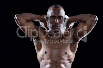 Portrait of shirtless athlete holding rugby ball behind head