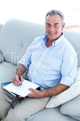 Happy businessman writing on notepad  at office