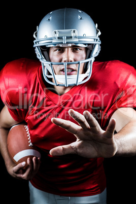 Portrait of American football player gesturing while holding bal