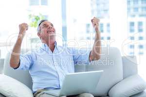 Happy man looking up while working on laptop