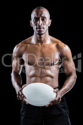 Portrait of serious shirtless athlete holding rugby ball