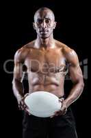 Portrait of serious shirtless athlete holding rugby ball