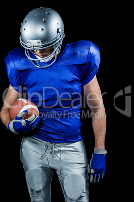 American football player looking down while holding ball