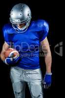 American football player looking down while holding ball